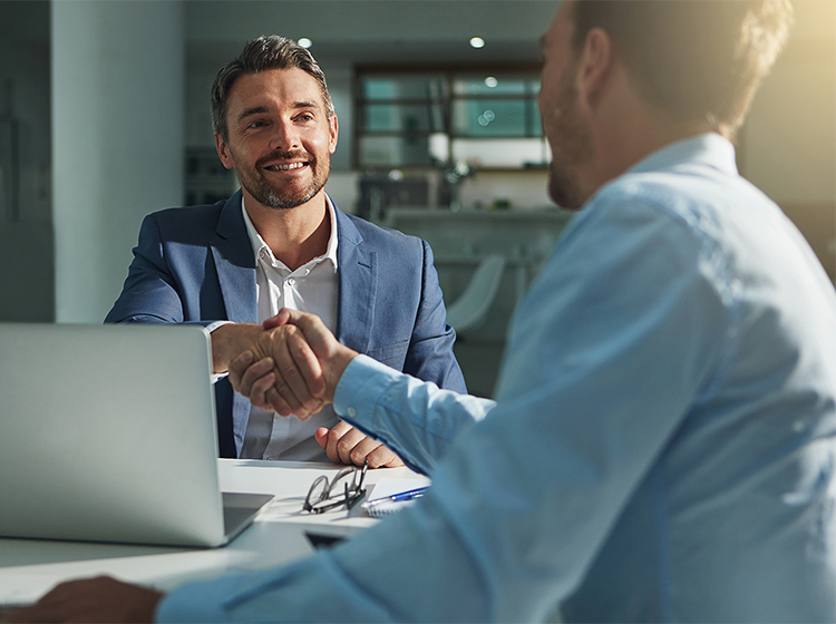 Two businessmen shaking hands over table