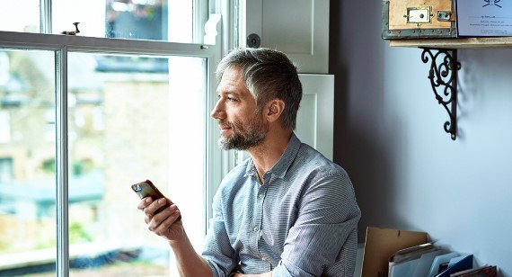 Man on mobile phone looking out of window